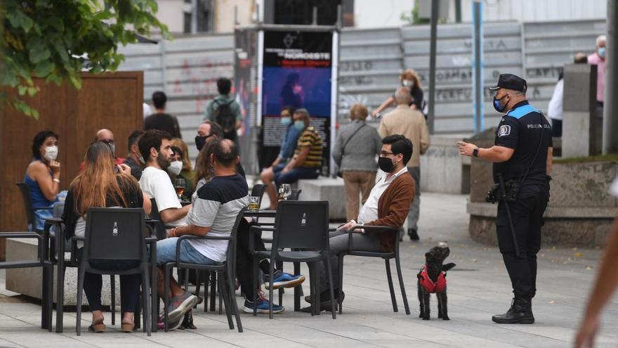 Un agente vigila a los clientes en una terraza de un establecimiento de hostelería en A Coruña.