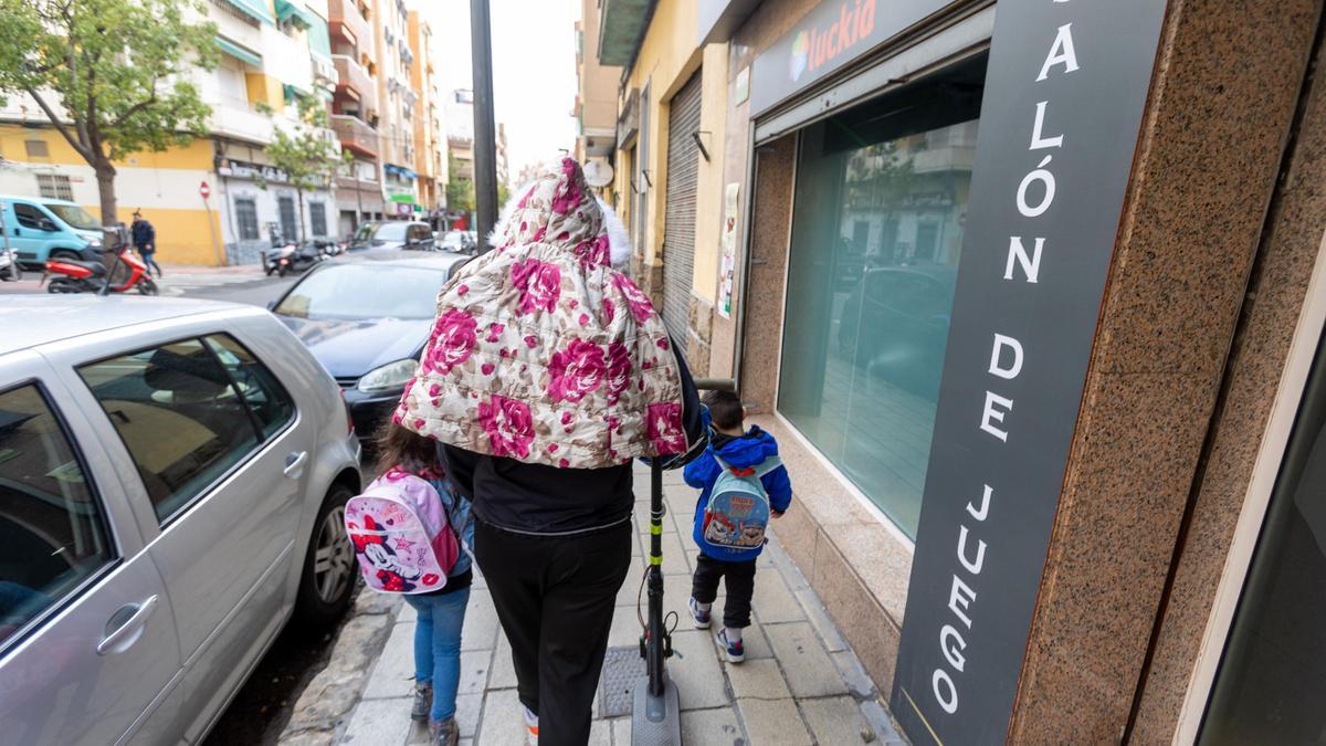 Una mujer pasa con dos niños junto a un salón de juego en Alicante.