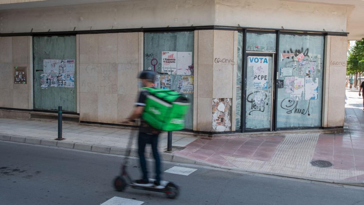 Un repartidor passa per davant d'una oficina bancària que va tancar portes