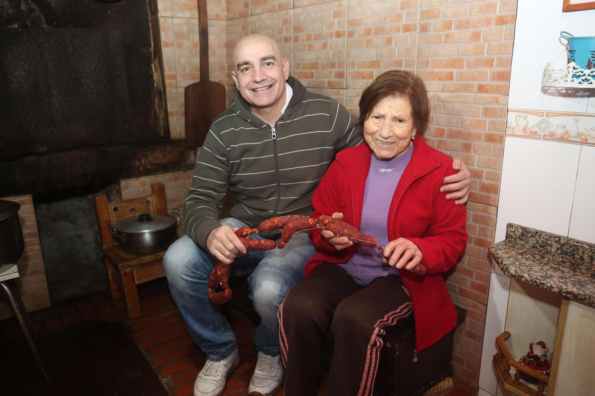 Pachi Patiño cunha das veciñas de Viós amosando os chourizos que se catarán na ruta
