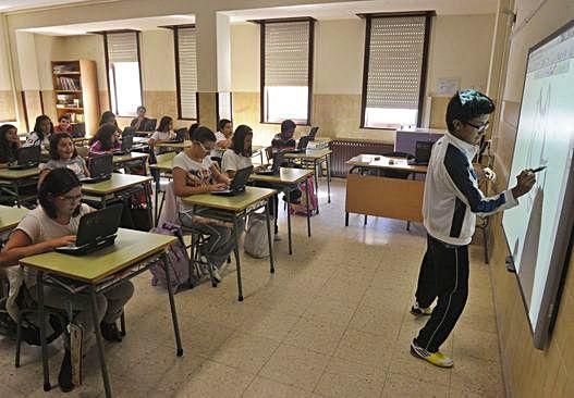 Niños en un aula utilizan los ordenadores y la pizarra digital.  V. E.