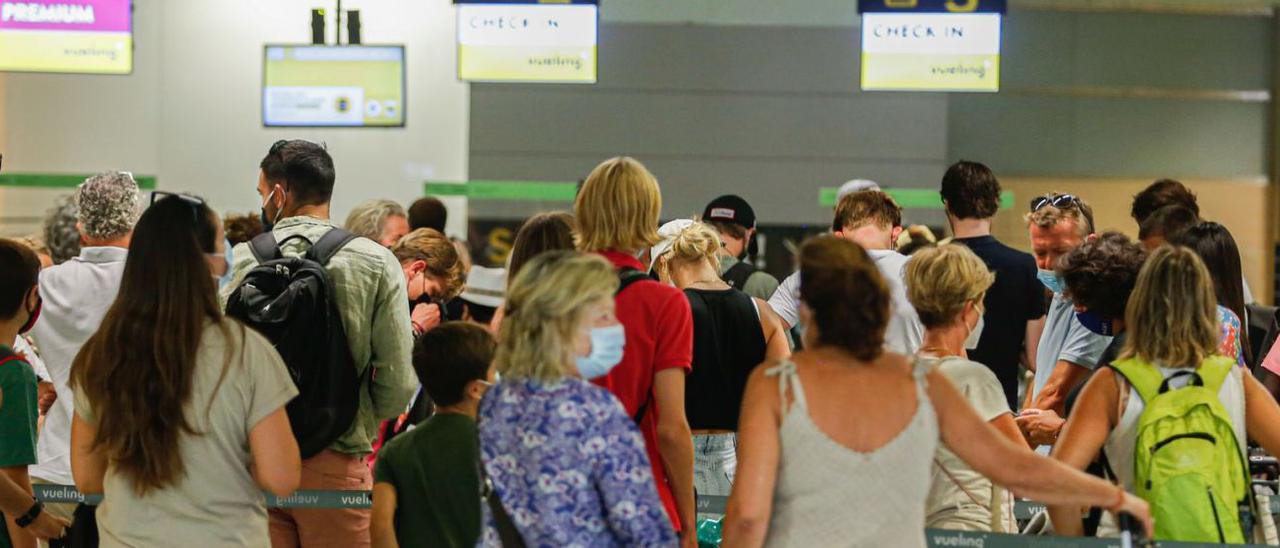 Viajeros esperando para facturar sus maletas en el aeropuerto de Eivissa, al comienzo de la temporada. | TONI ESCOBAR
