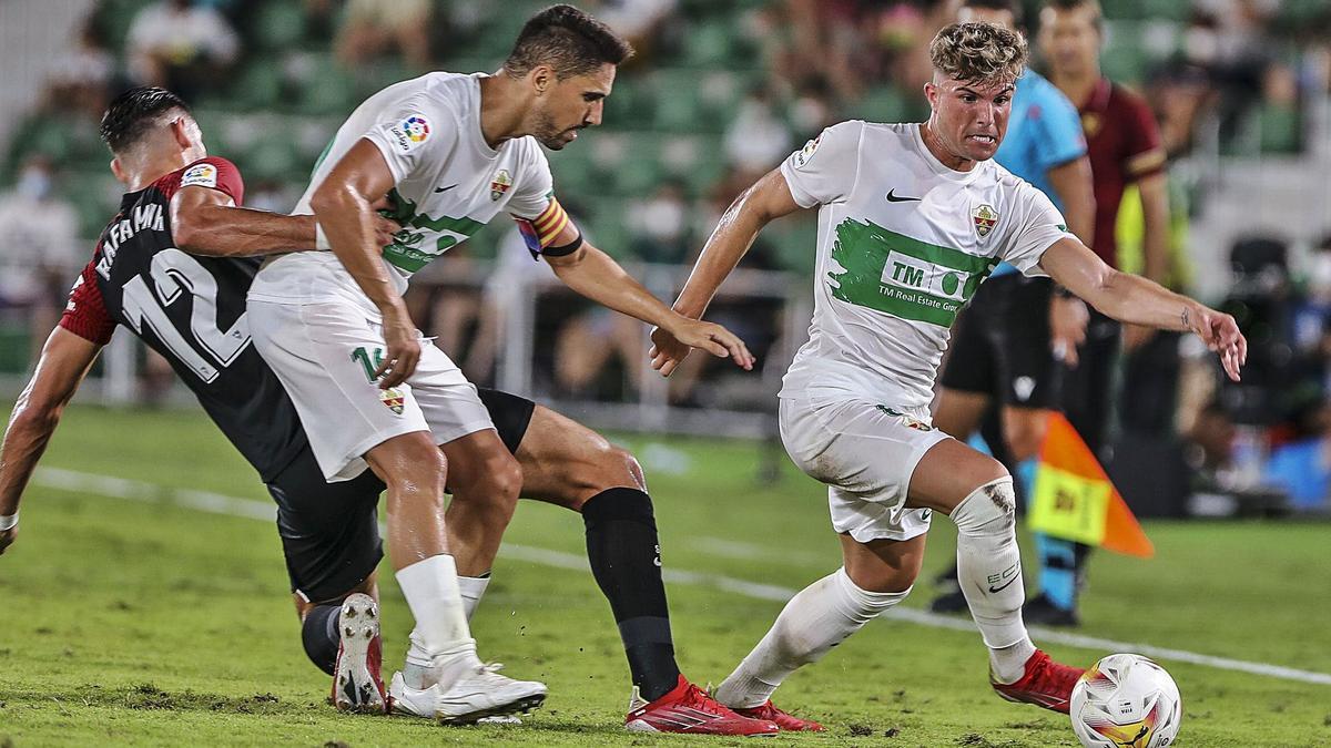 Raúl Guti se lleva un balón, mientras Fidel aguanta a Rafa Mir, en una demostración de la solidaridad defensiva que ayer mostró el Elche ante el Sevilla. | ANTONIO AMORÓS