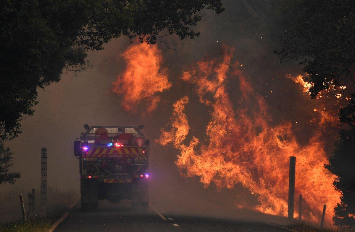 12 November 2019, Australia, Coffs Harbour: A fire truck passes by a bushfire near Nana Glen. Photo: Dan Peled/AAP/dpa