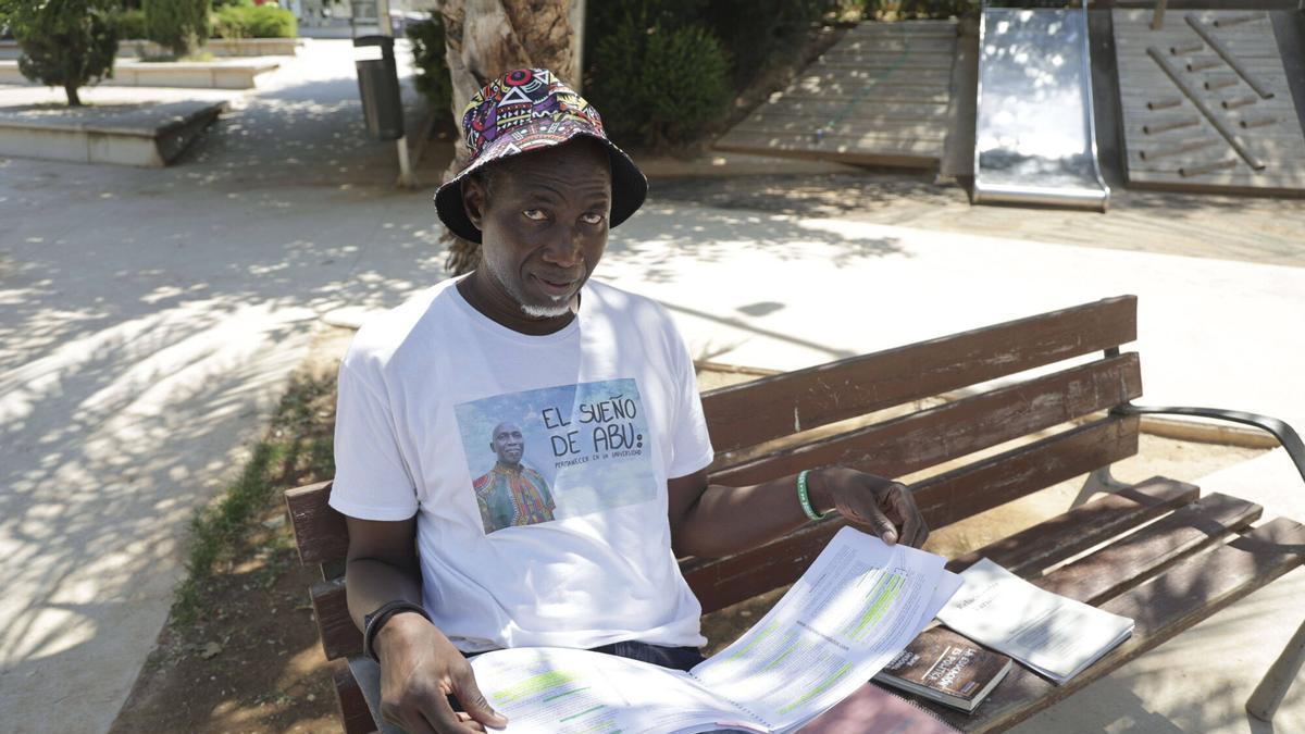Abu muestra sus libros y apuntes de la carrera en un parque de Orriols, el barrio en el que vive.