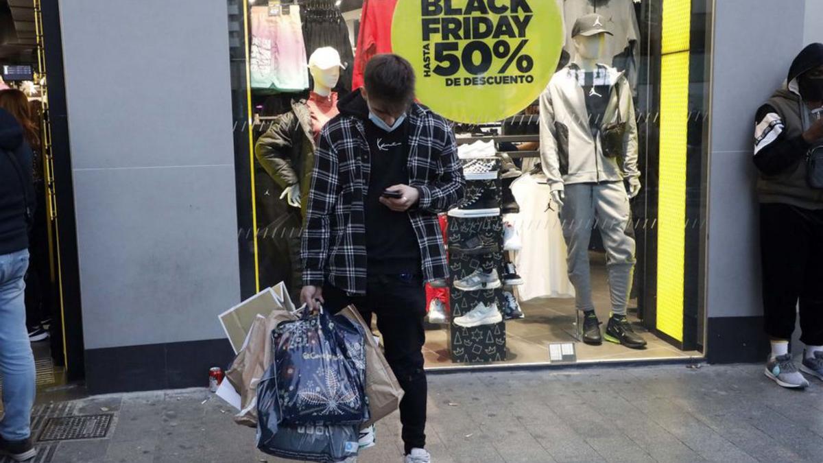 Un joven consulta el móvil durante el Black Friday en València. | M. Á. MONTESINOS