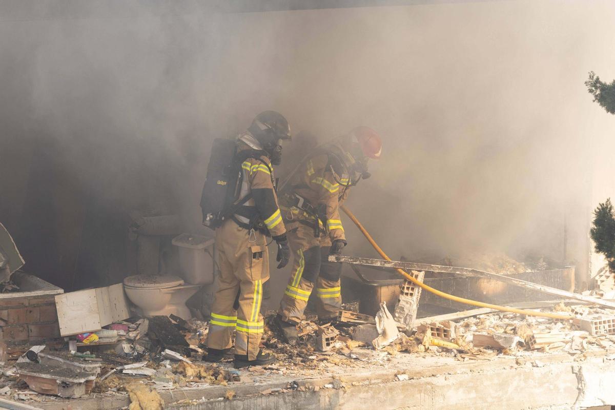 Los bomberos extingen las llamas de la vivienda.