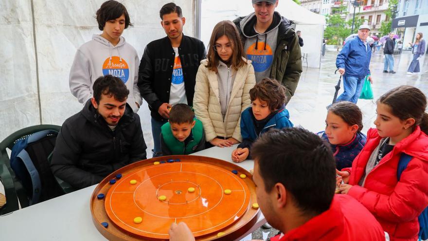 Raúl Santamaría, a la izquierda, juega con unos jóvenes bajo una carpa en la plaza de Galicia.   | // I.ABELLA