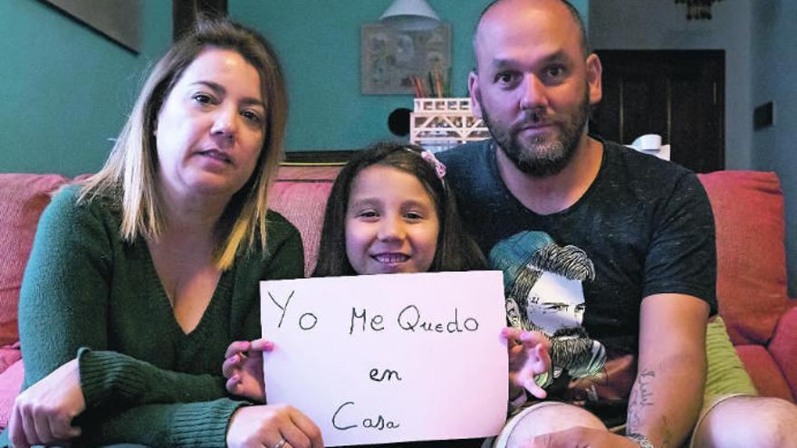 Cristi Morales y Pedro Arvelo con su pequeña Cayetana, que anima a todos a permanecer en casa con un cartel.