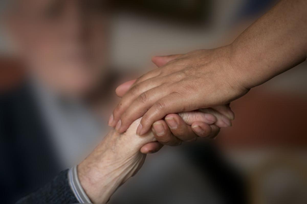 Un hombre le sostiene la mano a un enfermo