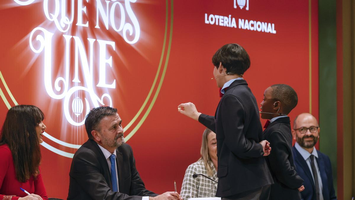 Los estudiantes de San Ildefonso Alonso Dávalos Durán (3d) y su compañero Ángel Abaga Elebiyo (2d) cantan el premio Gordo durante el sorteo de Navidad en el Teatro Real en Madrid, este jueves. EFE/ Javier Lizón