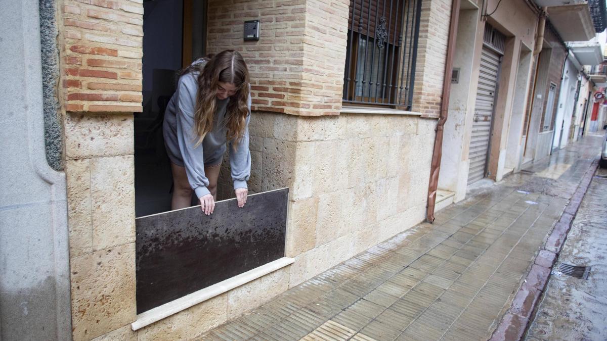 Una vecina de Algemesí instala una barrera para proteger su vivienda ante una posible inundación.