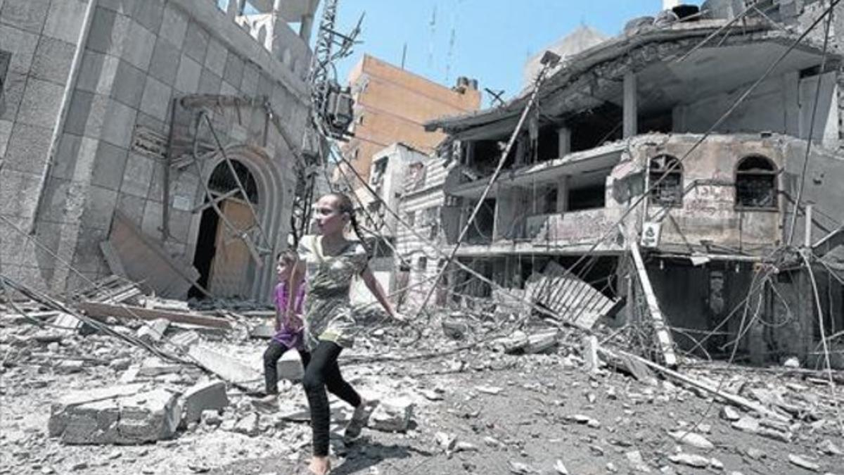 Dos niñas caminan entre los escombros que han dejado los bombardeos israelís en un barrio de la ciudad de Gaza.