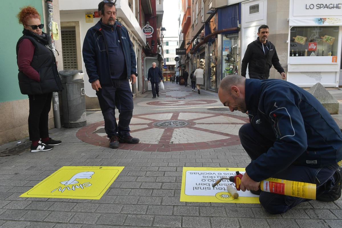 Operarios colocando carteles de la campaña "Este é o teu sinal"