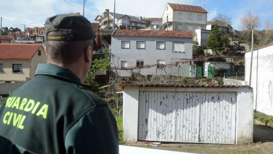 Un agente observa la casa y el galpón de la víctima, donde fue encontrado el cadáver. / rafa vázquez