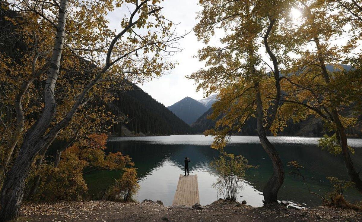 Un hombre toma una foto en un día de otoño en el lago Kolsai, en la región de Almaty (Kazajistán).