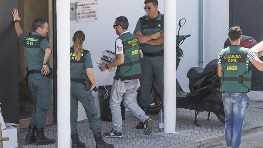 Varios agentes de la Guardia Civil entran en las oficinas de Amnesia con una máquina de contar dinero.