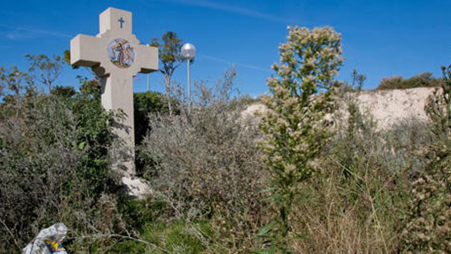 La cruz situada en la avenida de Dénia, frente al colegio Calasancio, casi está tapada por la maleza ya que hace meses que no se podan las hierbas, según los vecinos.