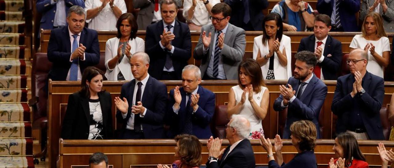 Pedro Sánchez, sentado, mientras su grupo aplaude alrededor.