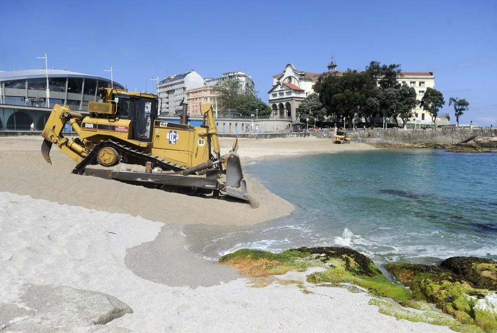 Las máquinas extienden la arena en la playa de Riazor.