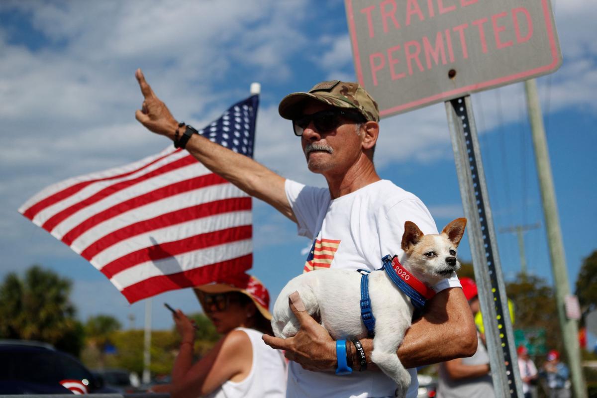 Joe González y su perro Asti se reúnen con los partidarios del ex presidente estadounidense Donald Trump cerca de la residencia de Trump en el Mar-a-Lago Club.