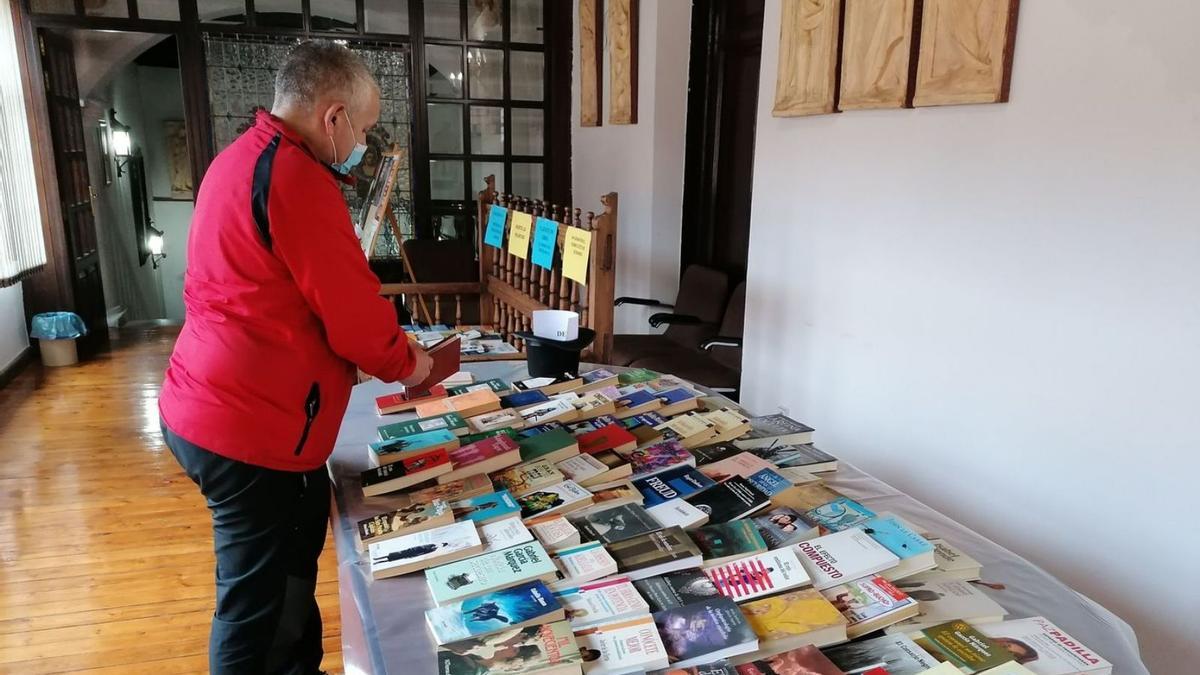 Un vecino consulta uno de los libros expuestos en el mercadillo solidario de la Casa de Cultura. | M. J. C.