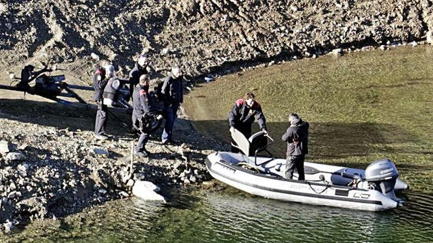 Els Mossos pugen el maniquí a la barca per fer la prova dels trets a la platja dels Xinesos, ahir al pantà de Susqueda.