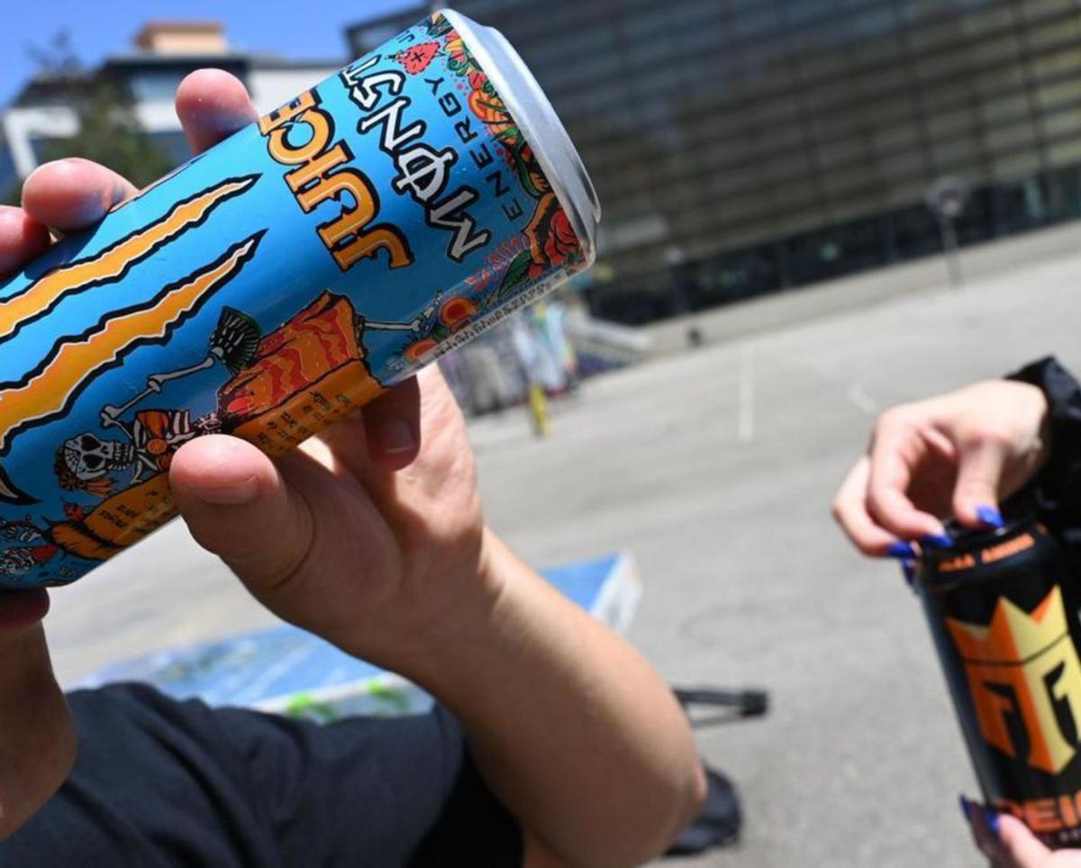 Dos jóvenes con sendas latas de bebidas energéticas.