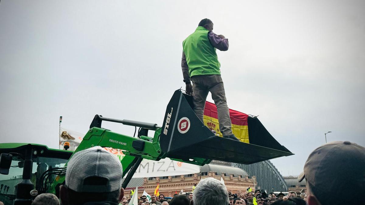 Un agricultor subido en la pala de un tractor durante las protestas de Madrid