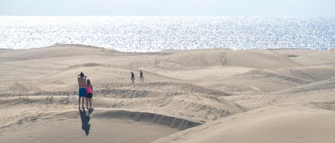 Una pareja de turistas fotografía las dunas de Maspalomas.