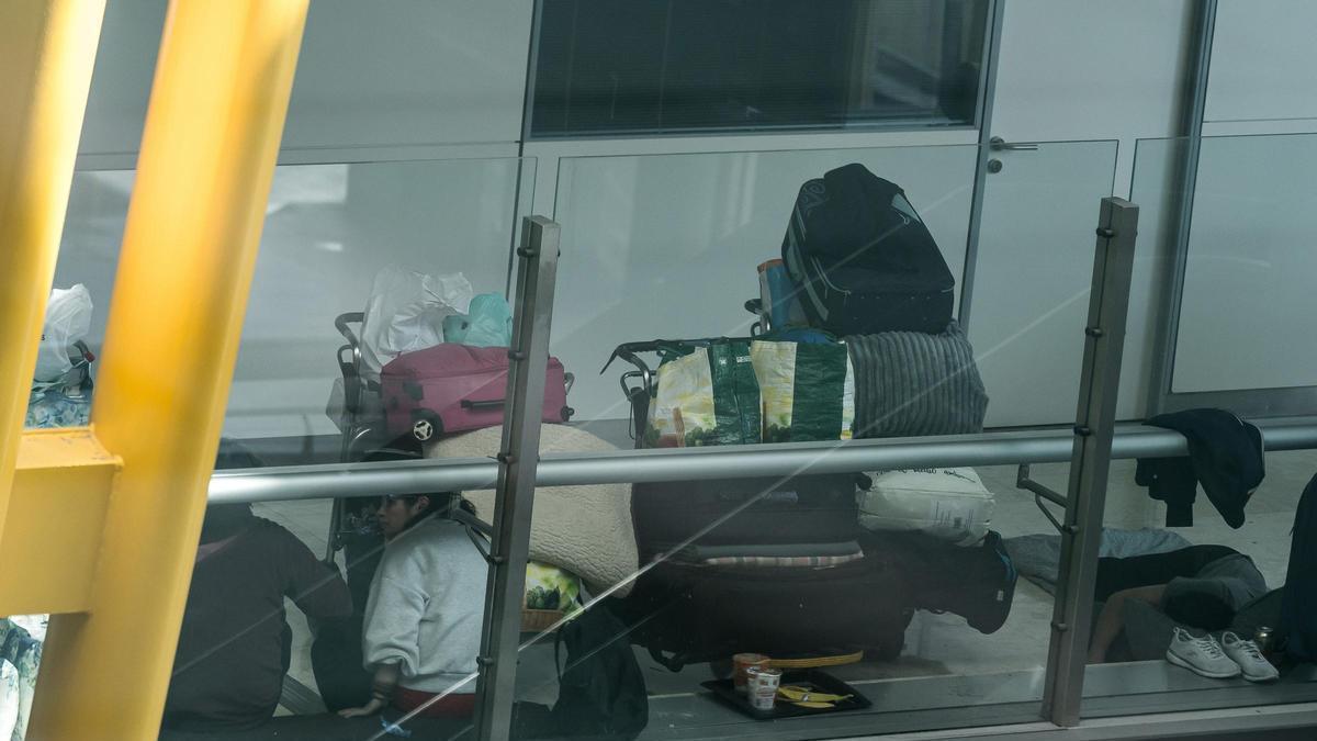 Archivo - Varias personas se preparan para pernoctar en la T4 del Aeropuerto Adolfo Suárez-Madrid Barajas, a 12 de mayo de 2025, en Madrid (España)