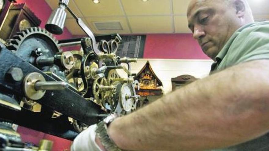 Juan Ramón Ruiz, en plena faena, con el reloj de la torre de las antiguas escuelas de Breceña, cuya restauración ultima en su taller avilesino.