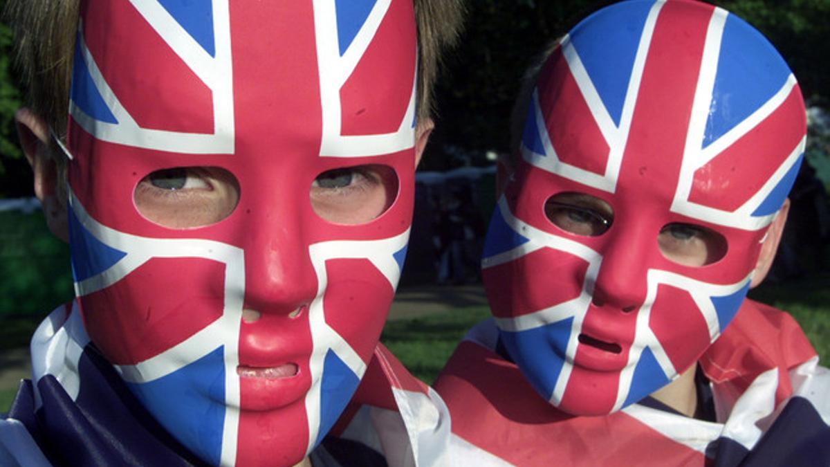 Dos jóvenes lucen máscaras con la bandera británica, en Londres.