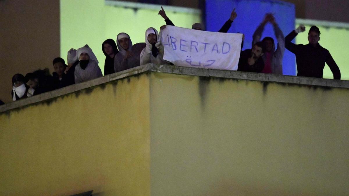 Algunos de los amotinados muestran un cartel que pide 'Libertad', en la azotea del CIE de Aluche.