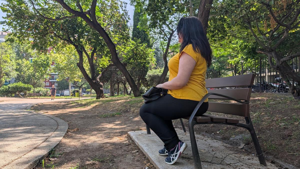 Lara sentada en unos jardines en València.