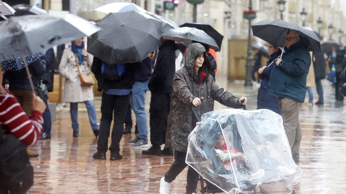 Varias personas se resguardan con paraguas.