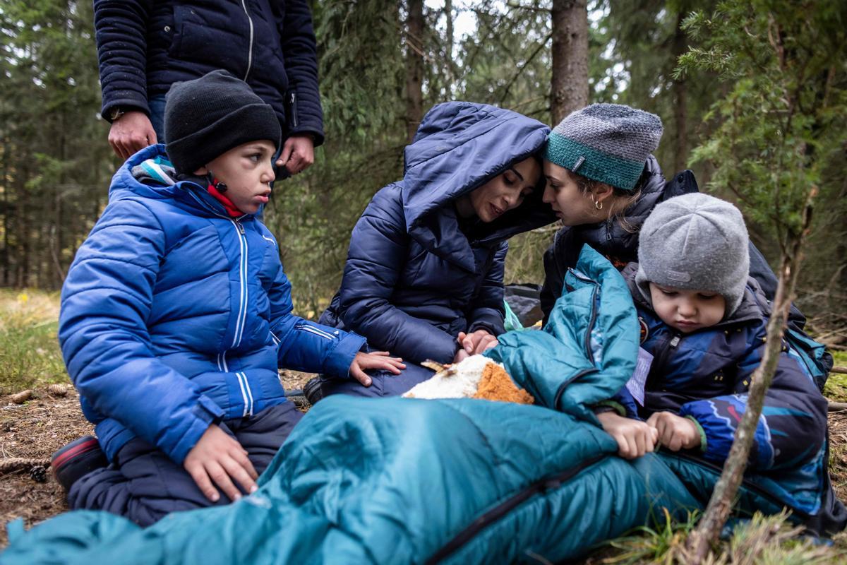 La familia Massini, originaria de Siria, recibe el apoyo de la activista Pamela (segunda por la derecha) de la asociación Grupa Granica, mientras esperan transporte en el bosque, cerca de la ciudad polaca de Kleszczele.