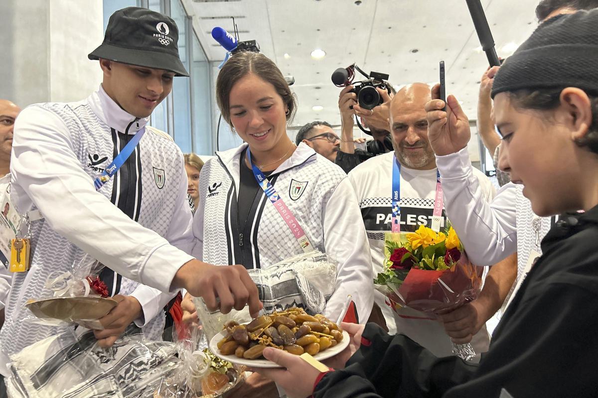 Los atletas palestinos Yazan Al Bawwab y Valerie Tarazi prueban una cita que les ofreció un joven partidario al llegar al aeropuerto Charles de Gaulle de París, en los Juegos Olímpicos de Verano de 2024, el jueves 25 de julio de 2024, en Roissy, al norte de París, Francia.