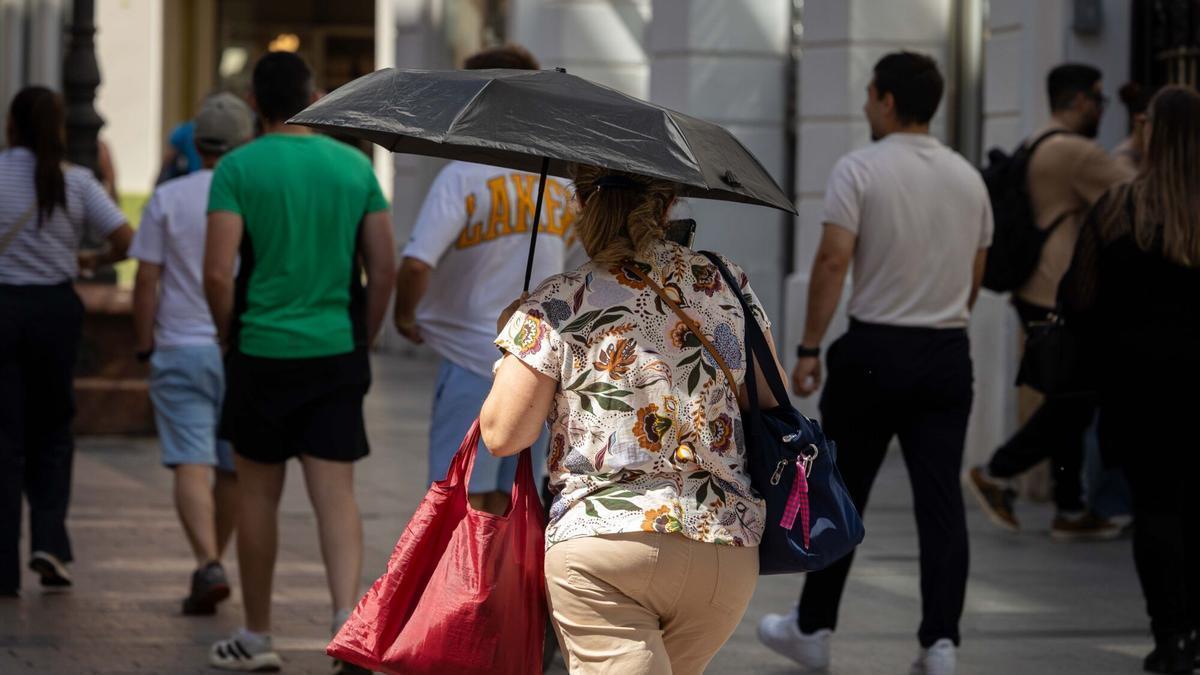 Una mujer se protege del sol con su paraguas.