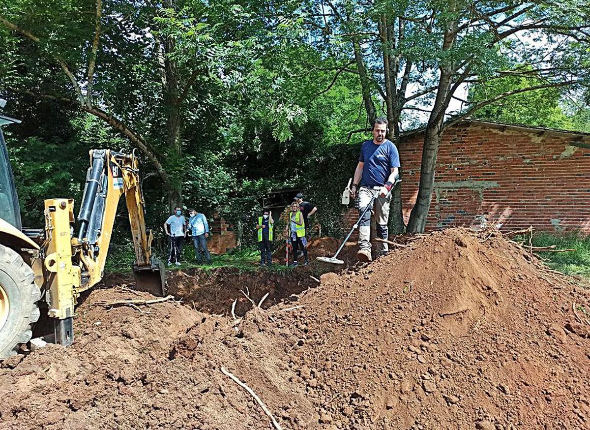 Arriba, Manuel Argüelles, junto a Malena García, de la ARMH, rellena el formulario para realizar la toma de muestras para la prueba genética. Debajo, uno de los arqueólogos, trabajando en una detección de metales en la tierra removida. | S. Arias