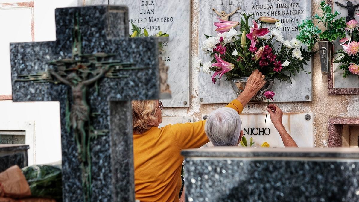 Familiares colocan flores en un nicho en el cementerio de Santa Lastenia.