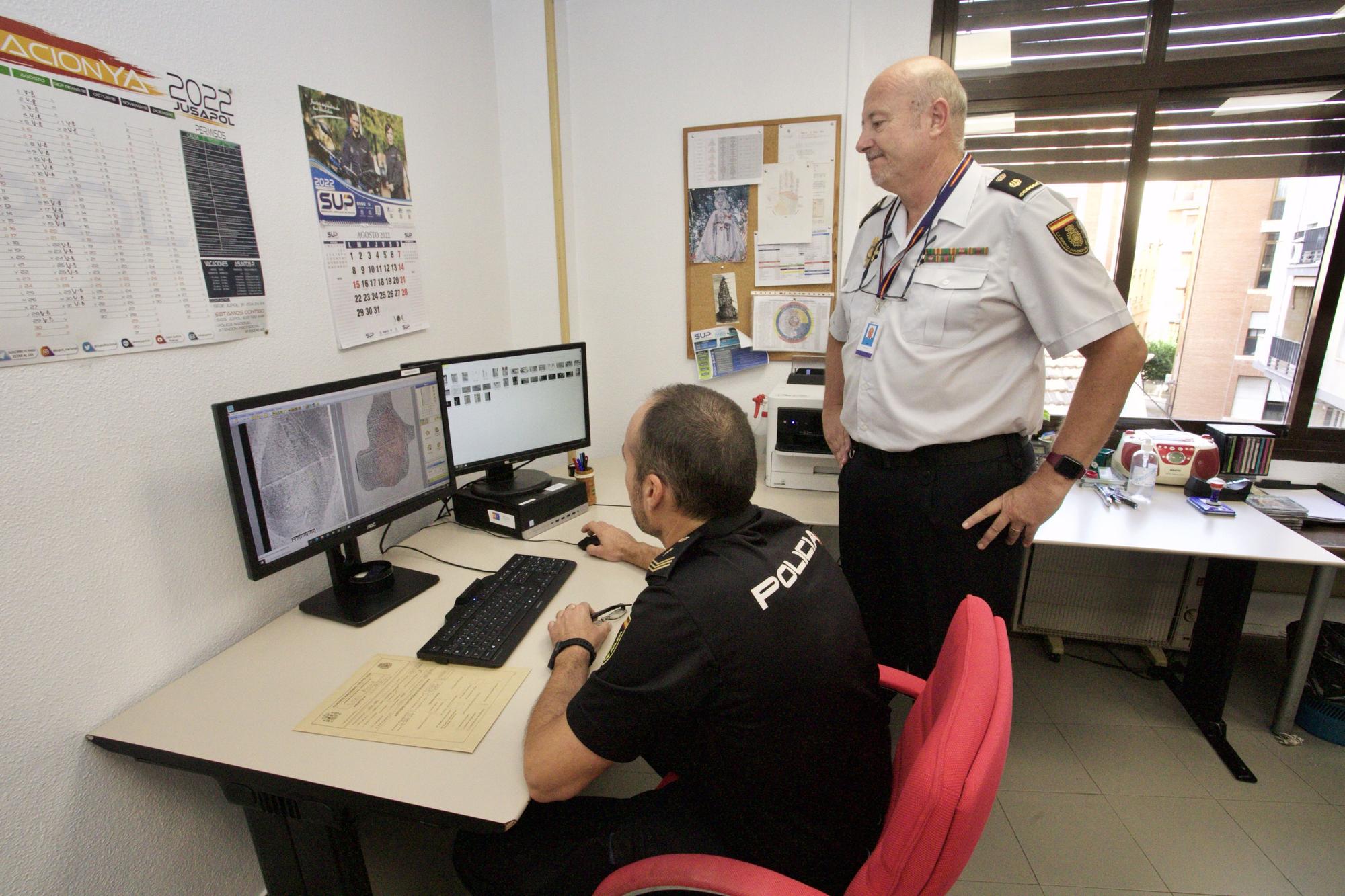 El jefe Carvajal mira cómo un policía trabaja con el sistema Said de identificación de huellas.