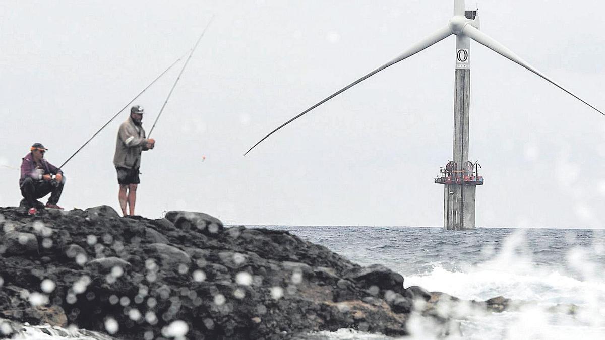 Pescadores, en primer término, y, al fondo, el aerogenerador que la ingeniería Esteyco prueba junto a la Plocan.