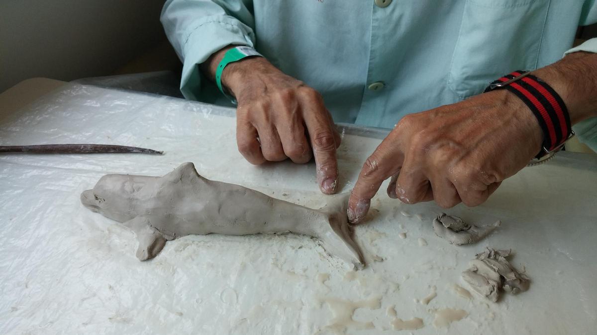 Un paciente de la Unidad de Cuidados Paliativos del Hospital de Sant Pau esculpe un delfín durante una sesión de arteterapia