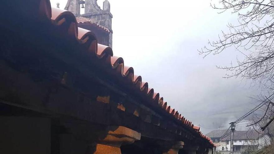 Un niño pasa por el exterior de la iglesia de Caleao, con las tejas rotas en el suelo.