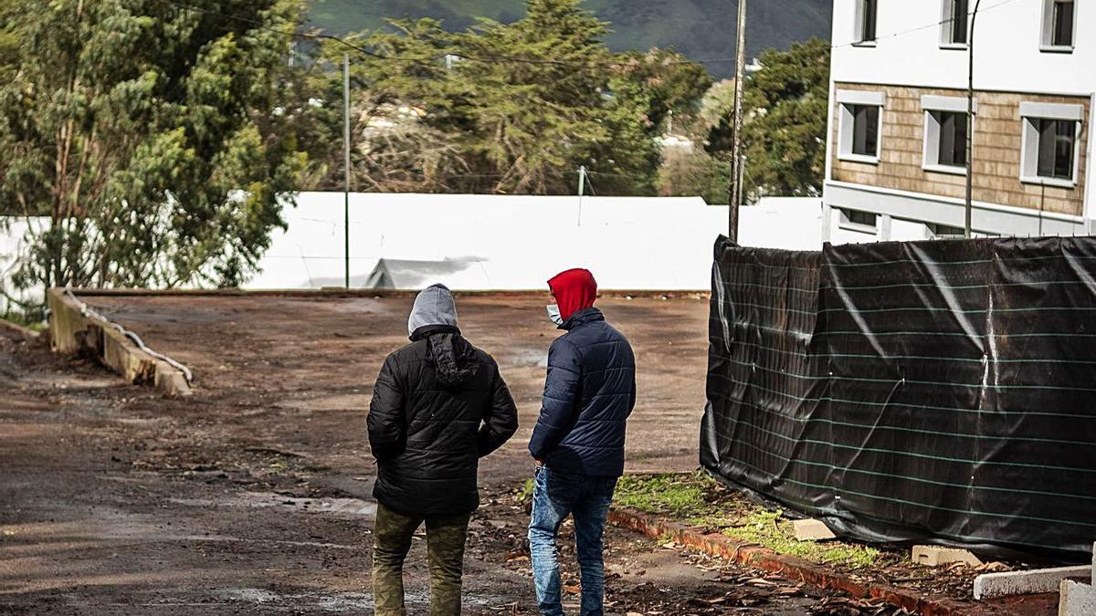 Dos hombres caminan hacia el interior del campamento de Las Raíces en la mañana de ayer.