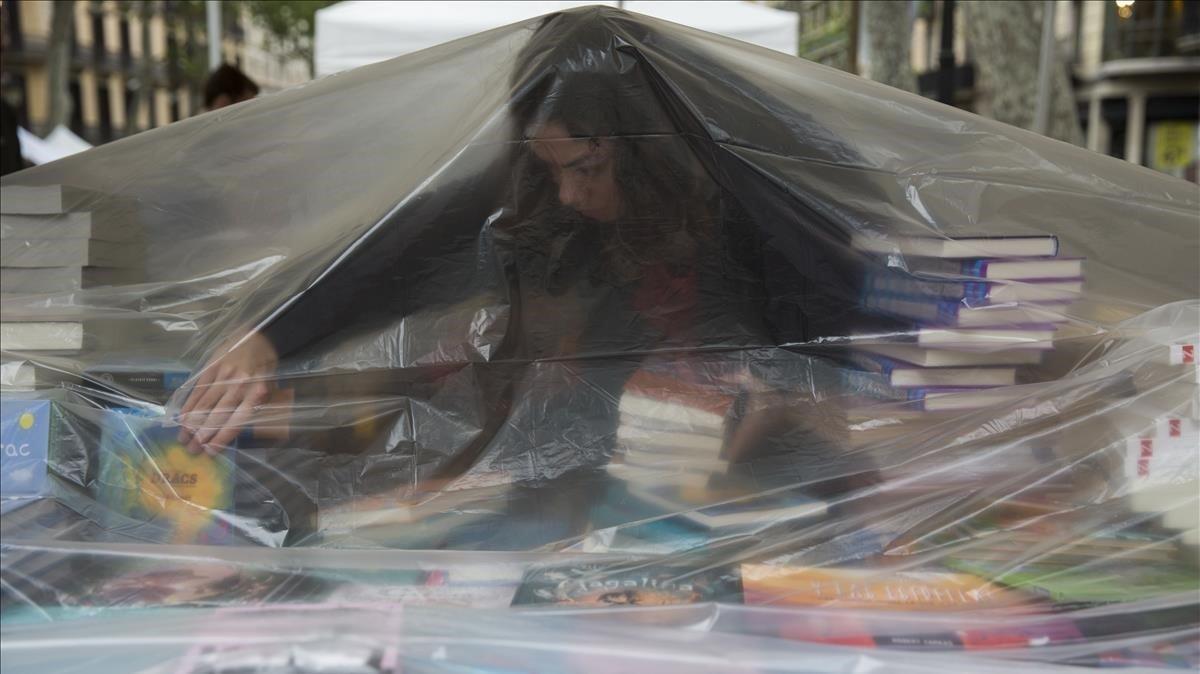 Una librera se protege de la lluvia caída a primera hora en Barcelona.