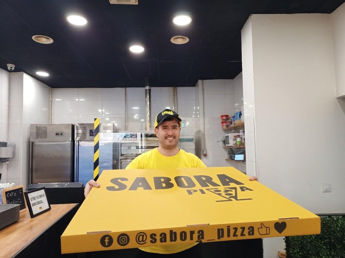 Raúl, encargado de Sabora Pizza, con una caja de una pizza de 80 centímetros