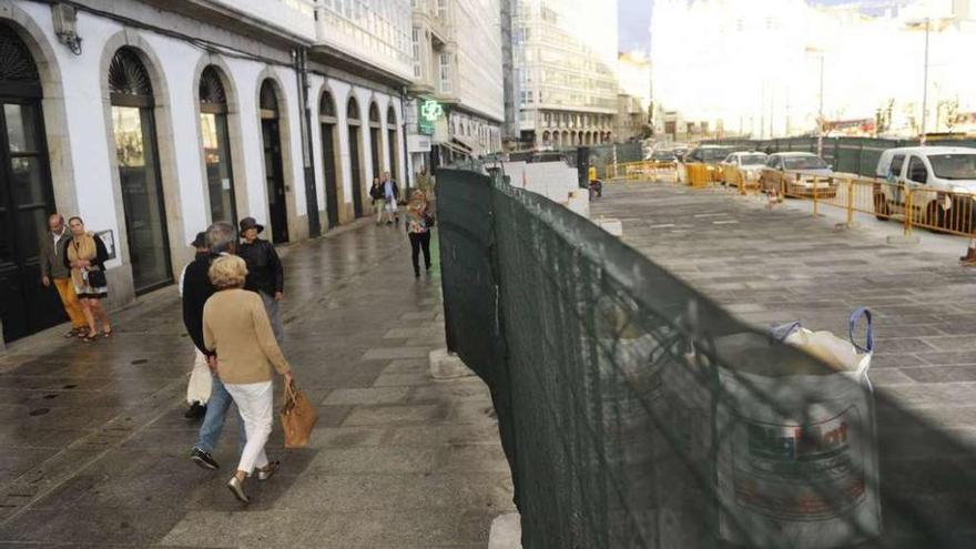 Vecinos pasean, ayer, ante las vallas de obra de la Marina.