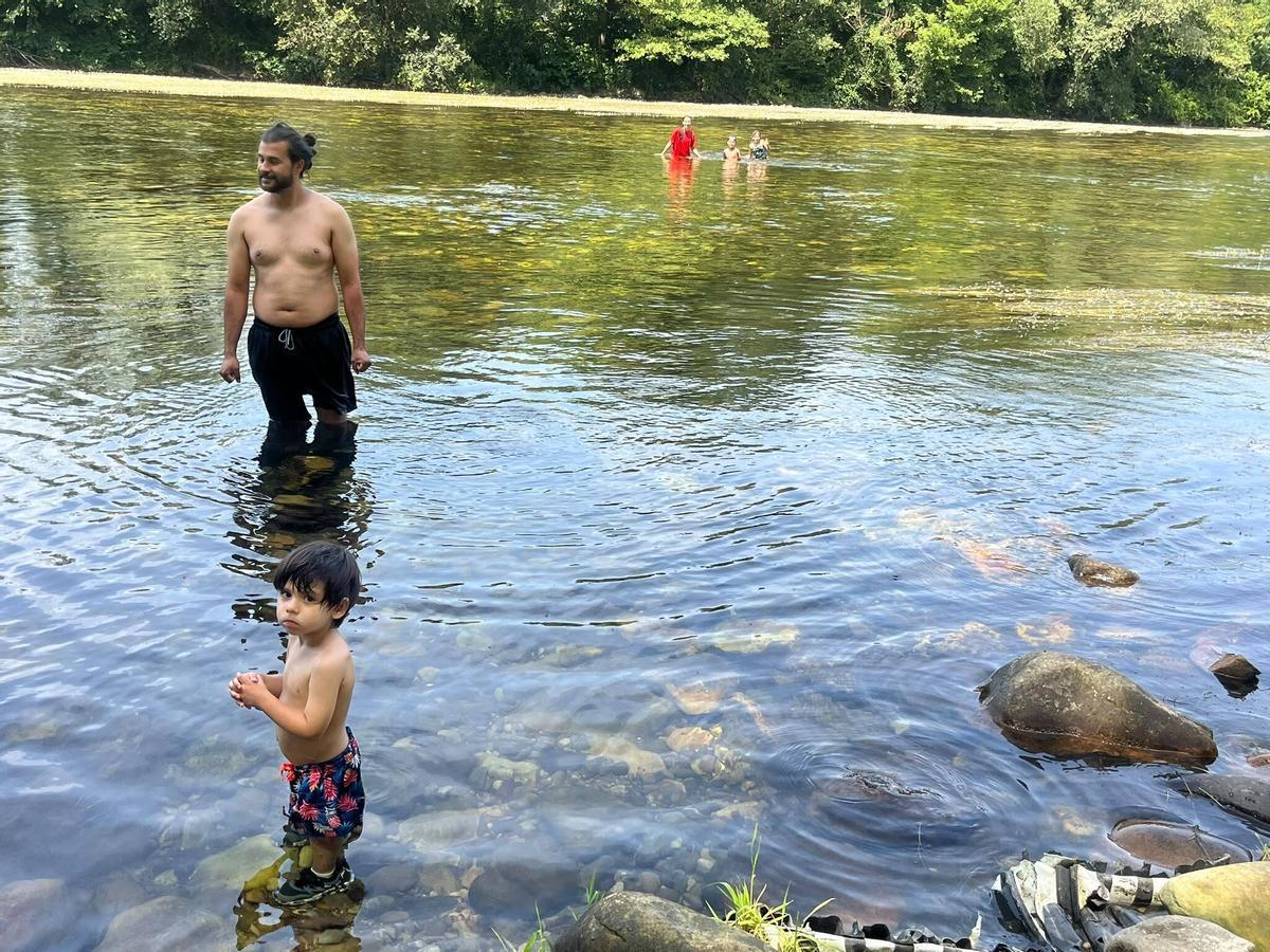 Cristian Cepas, con su hijo Lucas; al fondo, Diana Orozco y sus hijos Jacobo y Ania, bañándose en el Narcea.